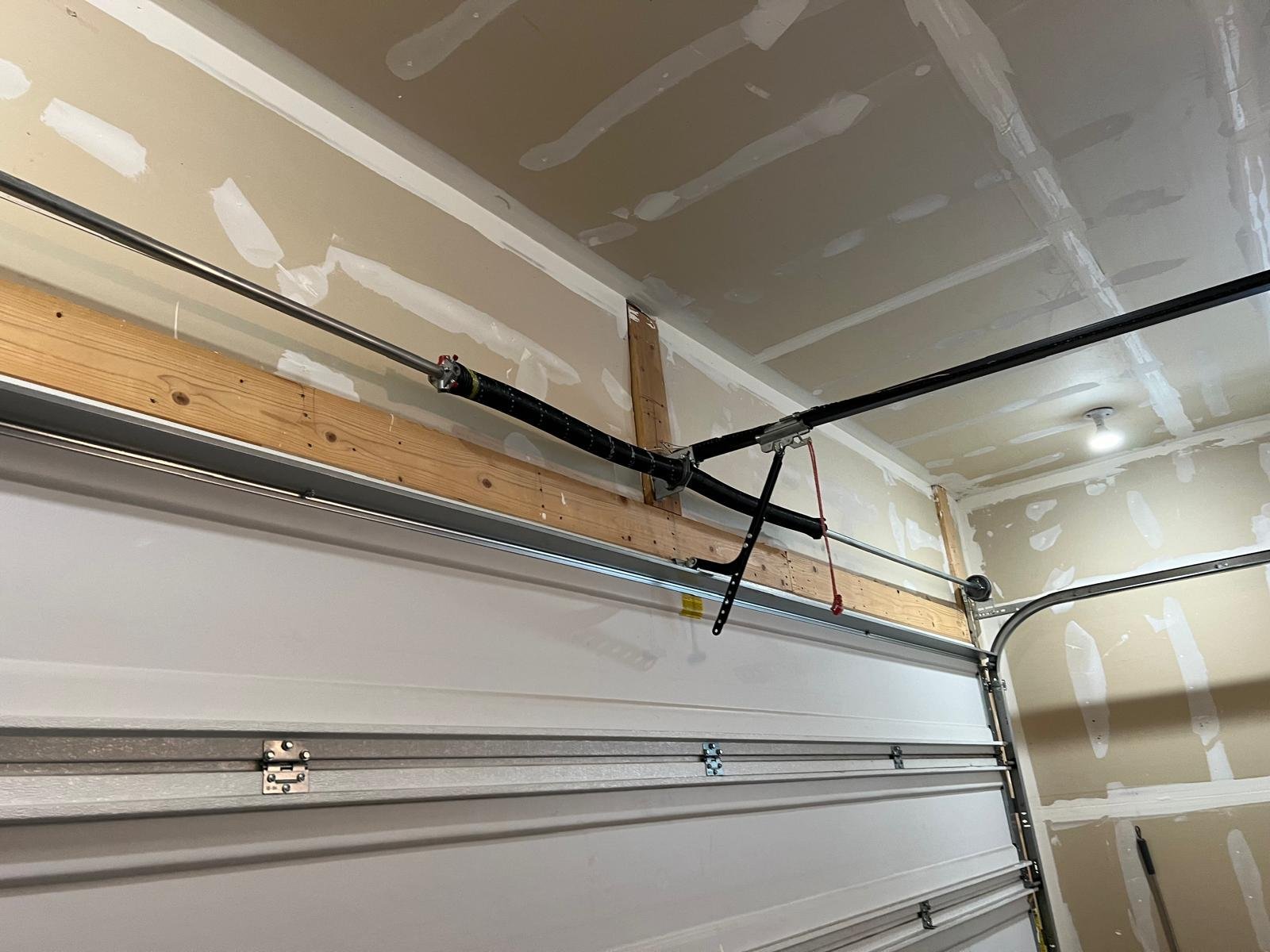 Torsion spring system mounted above a residential garage door