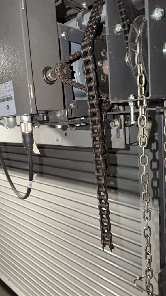 Garage door spring and lifting hardware mounted beside a sectional door